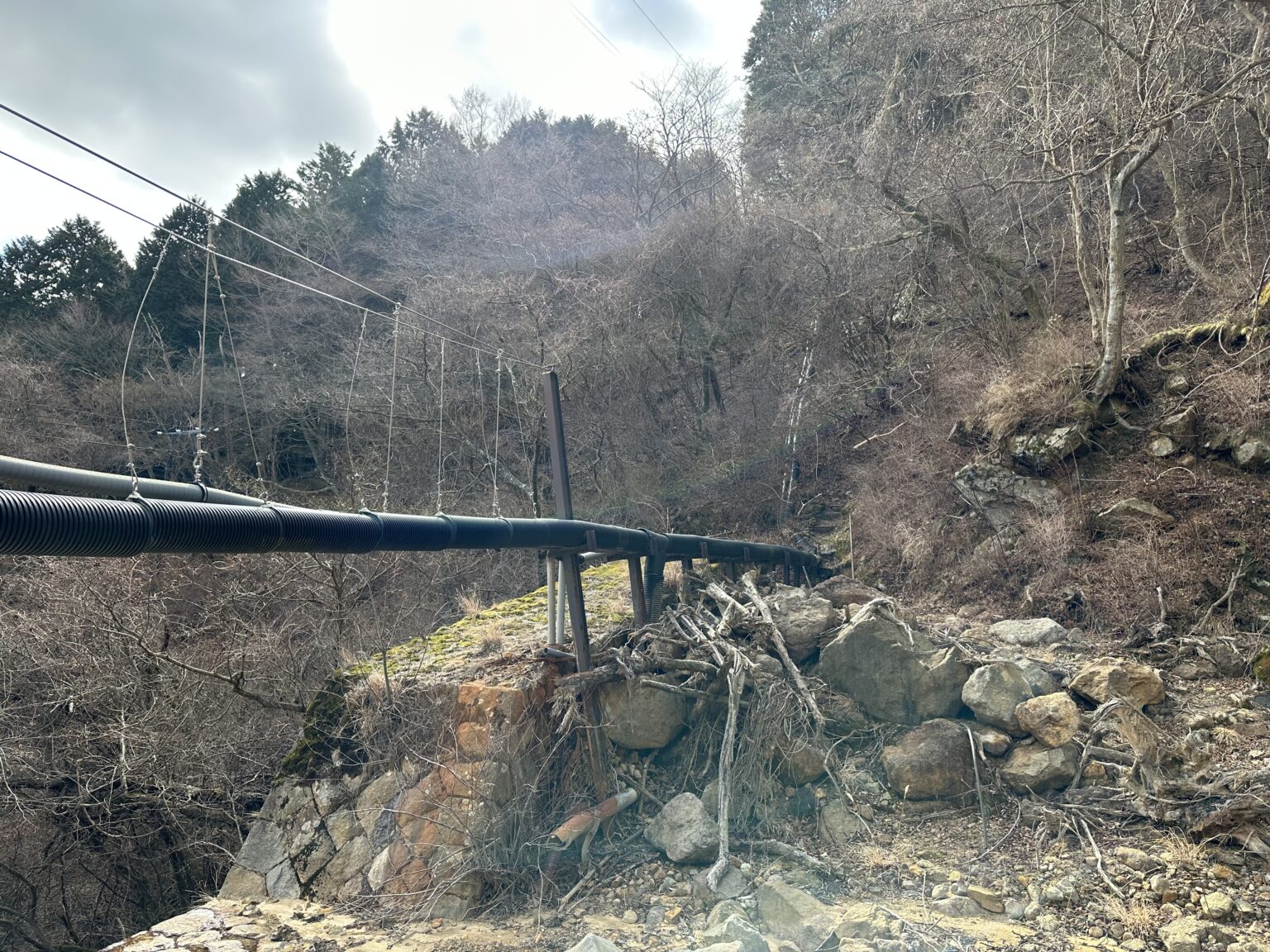 谷を渡る配管と荒れた沢沿い。雨天後は危険なルート